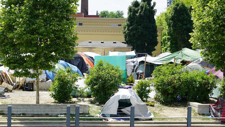 Tents set up in a lot with trees beside a building