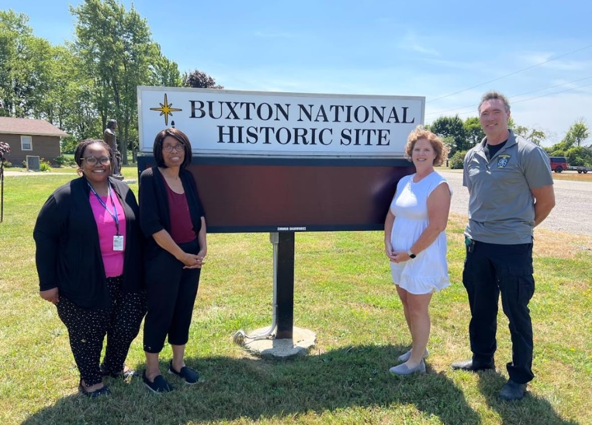 Funcionários da MobileCare do lado de fora da placa do Sítio Histórico Nacional de Buxton, em North Buxton, Ontário.