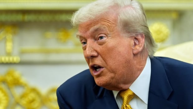 Yellow haired man in blue suit and gold time, speaking