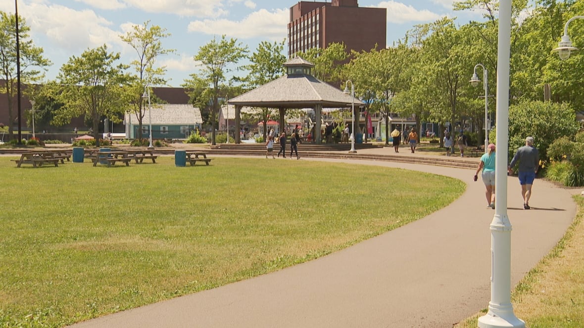 A small gazebo in front of grass and a walking path