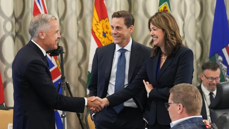 Un hombre y una mujer se ríen y se dan la mano y otro hombre se encuentra en ellos.