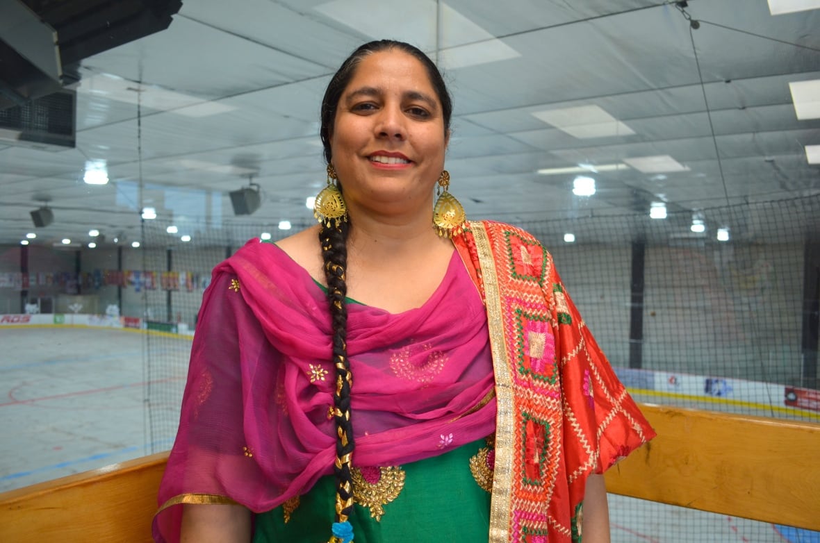 A woman with a long braid hanging down her side, wearing a pink and green saree.