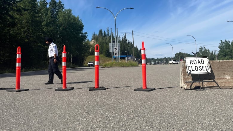 Four orange pylons are stretched across a road with a sign that says, Road Closed.
