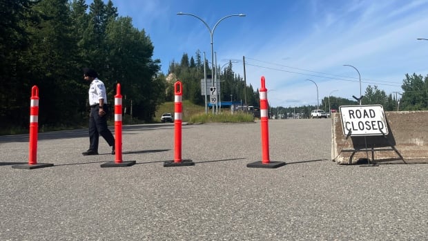 Four orange pylons are stretched across a road with a sign that says, Road Closed.