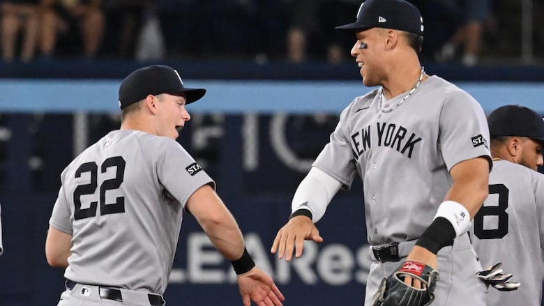 Two men's baseball teammates slap hands in celebration.