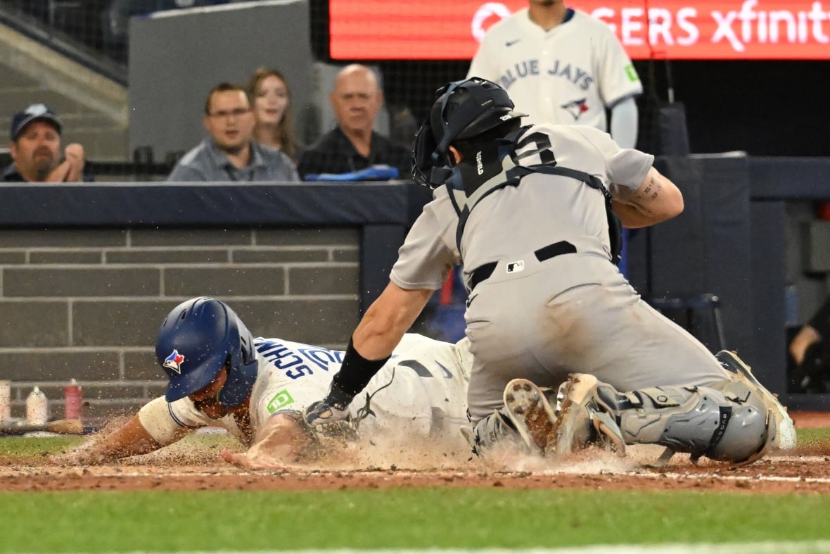 A men's baseball player is shown sliding into home plate, head first, creating a cloud of dust as a catcher applies a tag.