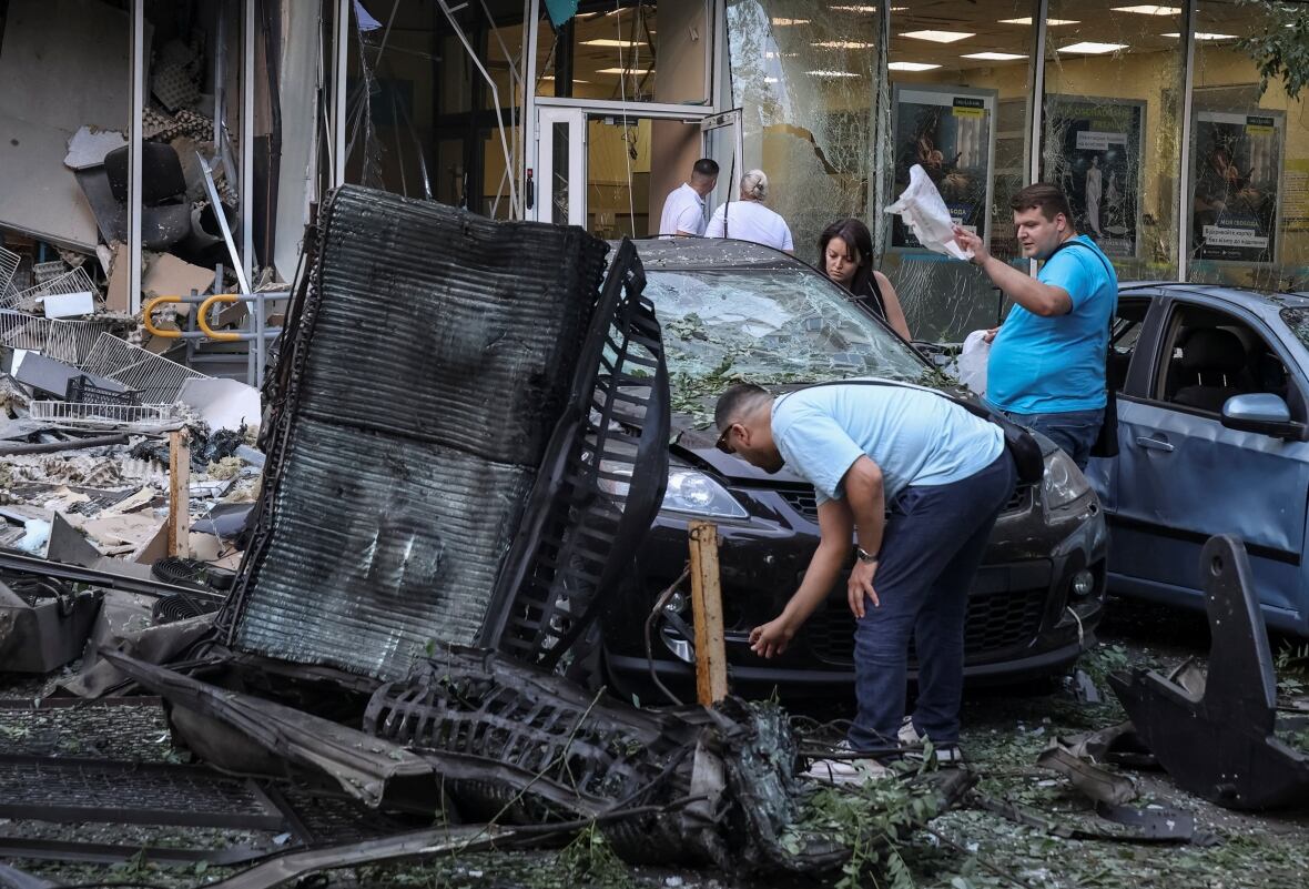 Two men and a woman examined a very damaged car with a cramped wind, during the injured urban vehicles.