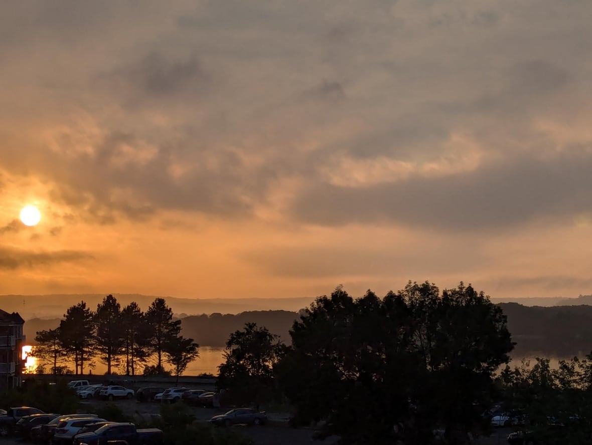 A cloudy sunset view overlooking the water and a parking lot