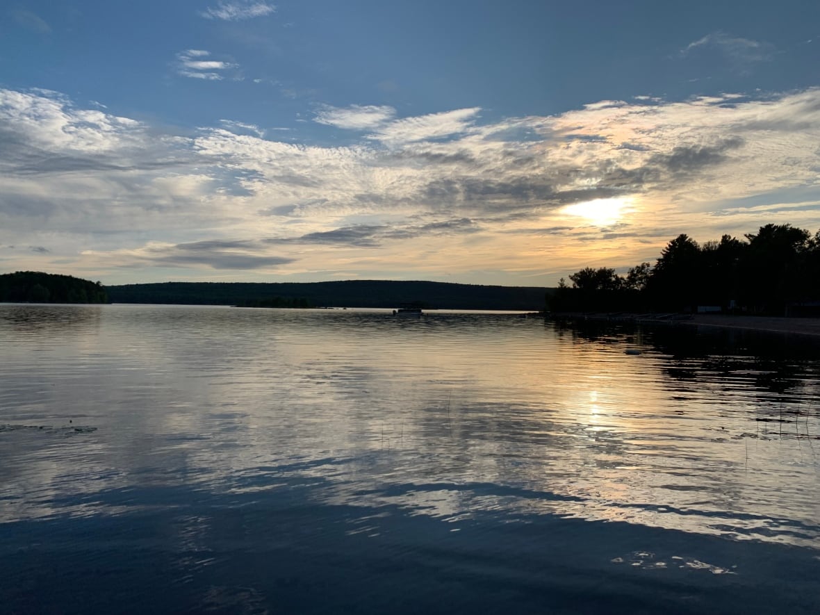 A lake with trees around it and clouds overhead