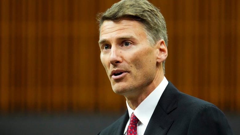 Photo of a man in a dark suit, white shirt and red tie