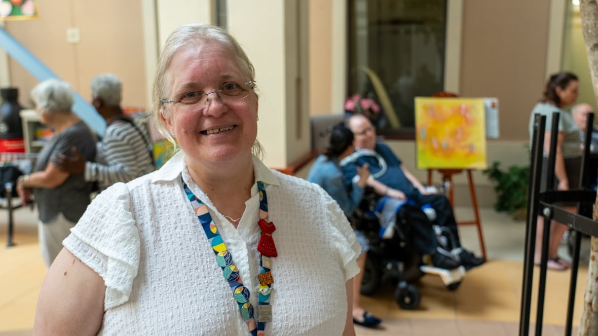 Chaplain Roshene Lawson standing at the Hallways of Hope art exhibit, with attendees visible behind her.