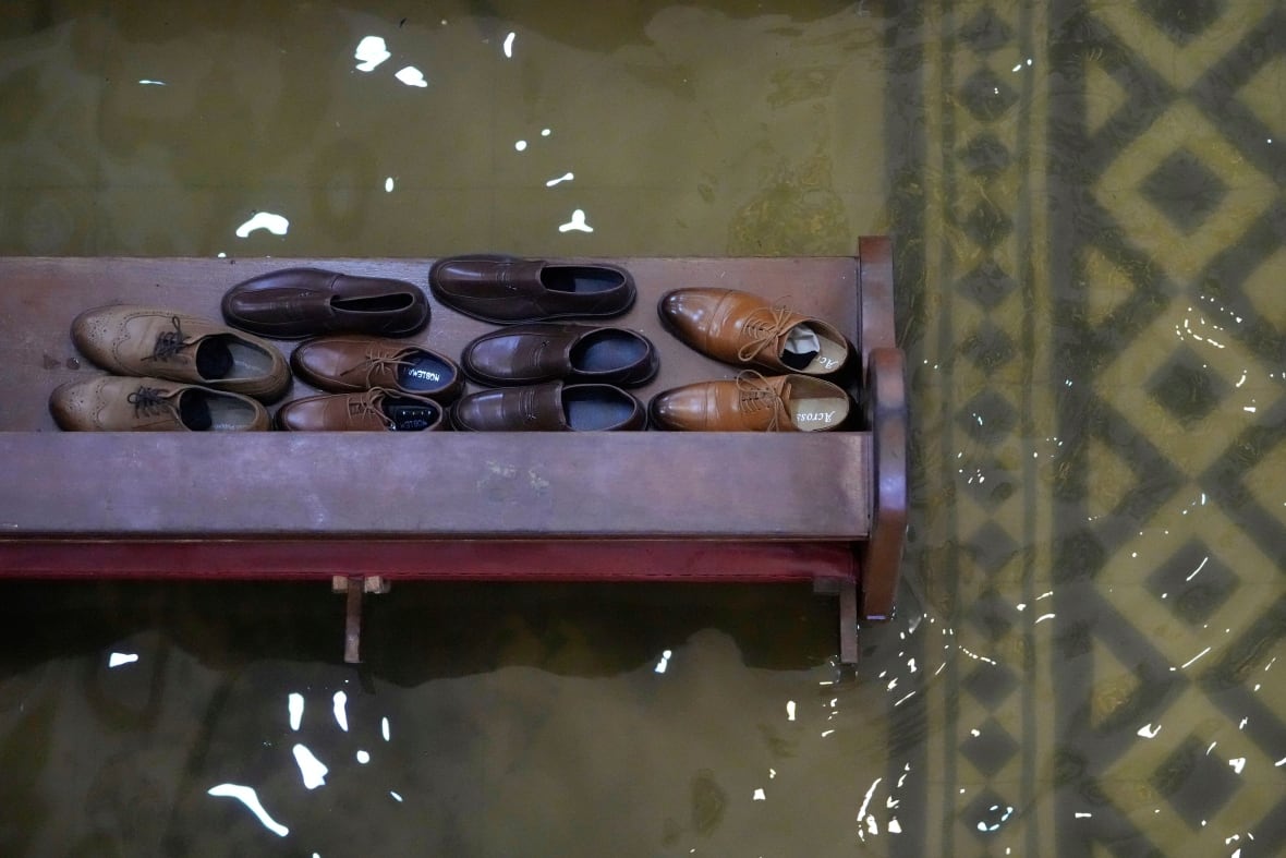 Brown shoes sit on a bench near water on a tiled floor.