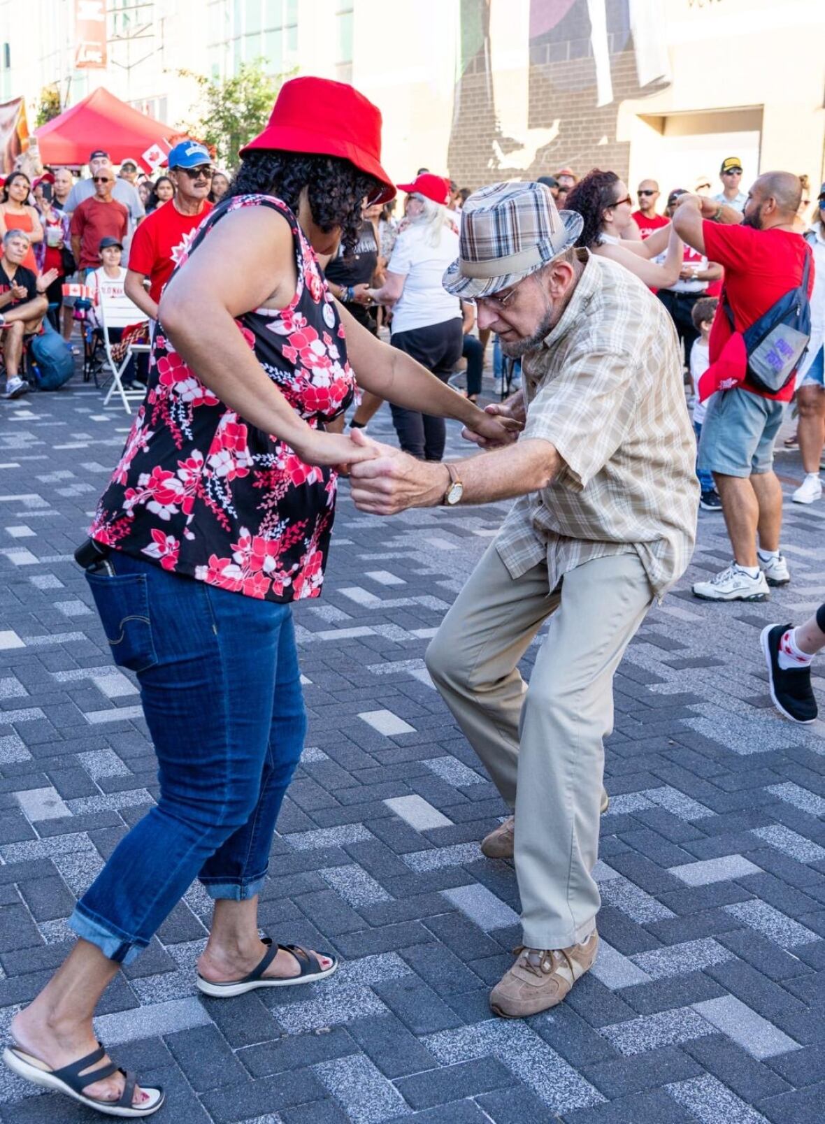 Un hombre baila con una mujer en una calle al aire libre.