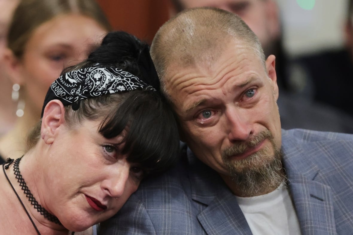 Close up of a crying man with a woman leaning on his shoulder