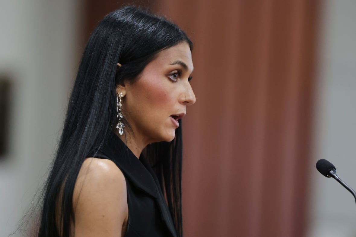 Profile view of woman with long straight dark hair, speaking into a microphone