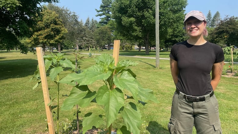 A smiling woman standing next to a newly-planted fruit tree
