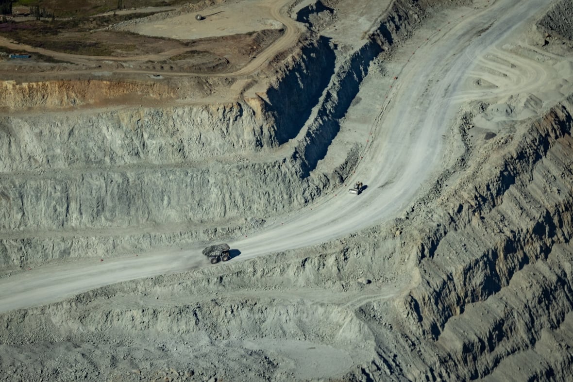 A mining truck drives across an open pit mine.