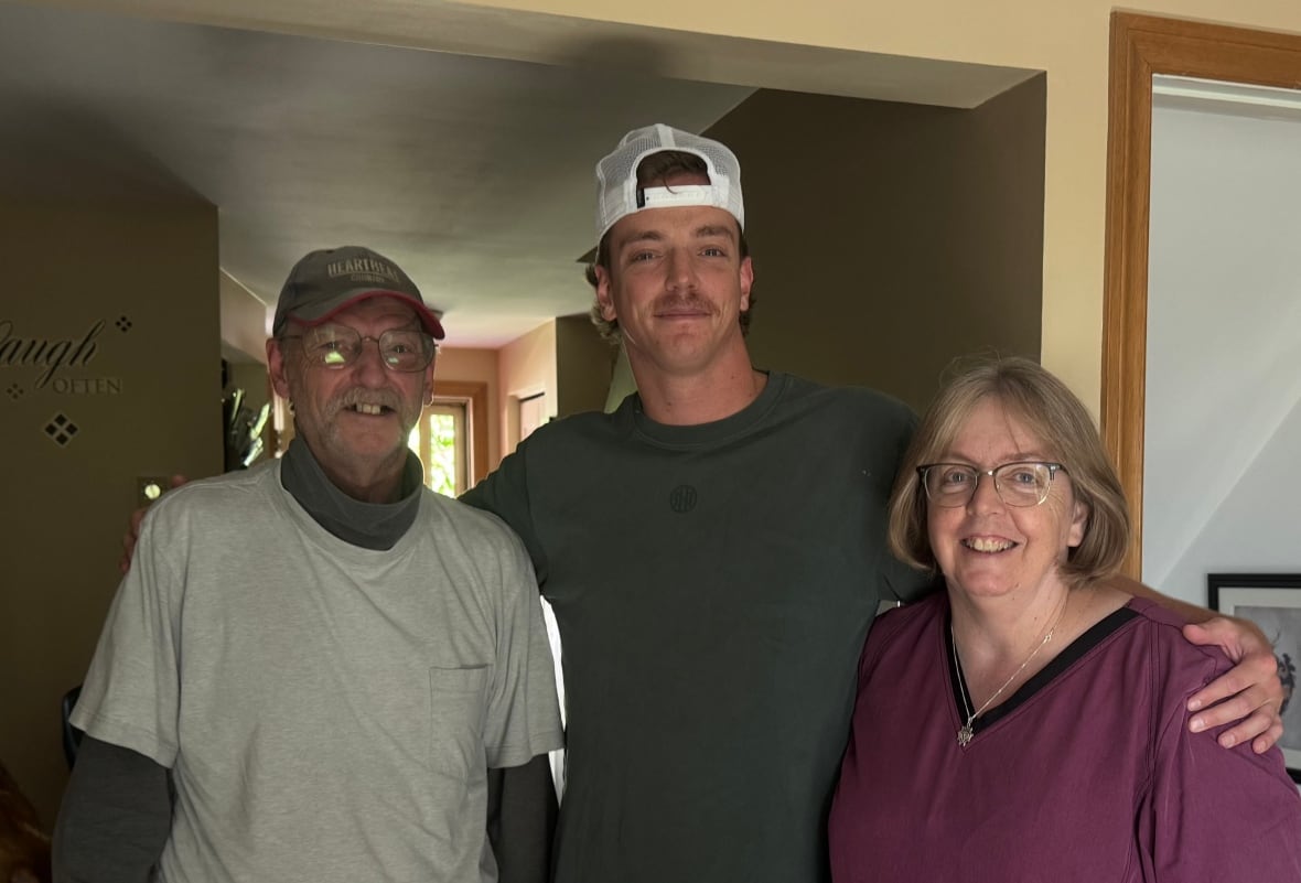James standing between his parents with his arms around them