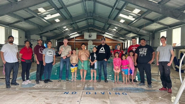 Kids and adults stand poolside. 
