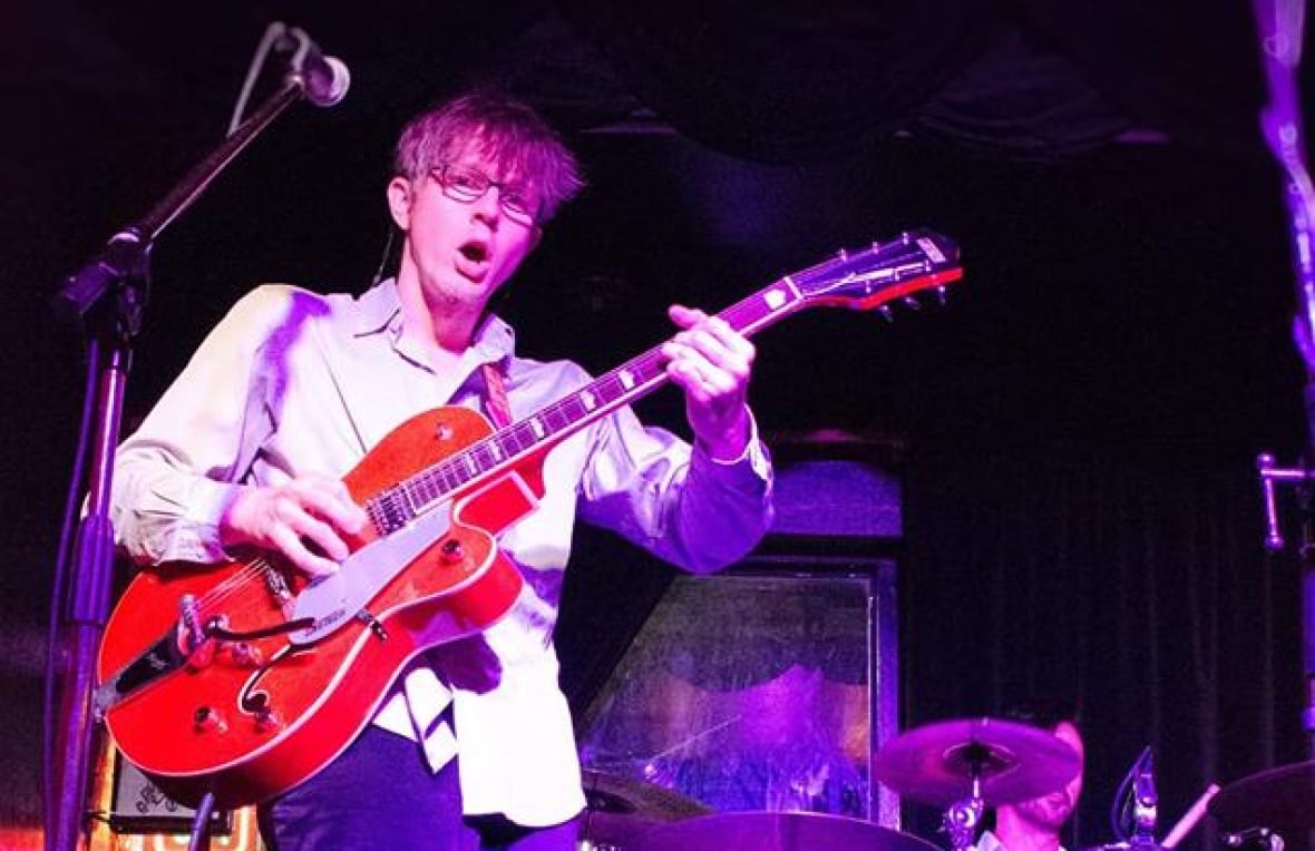 A person plays a guitar on a stage.