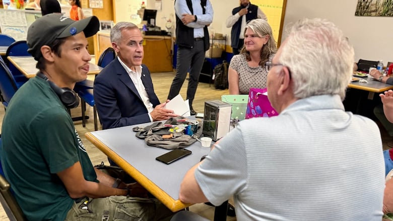 The prime minister sits at a table with three people