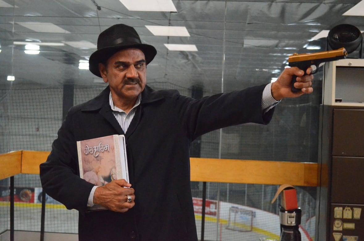 A man dressed in a hat and long coat holding out a gun