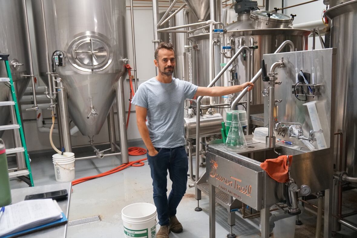 A brewer leans against his equipment