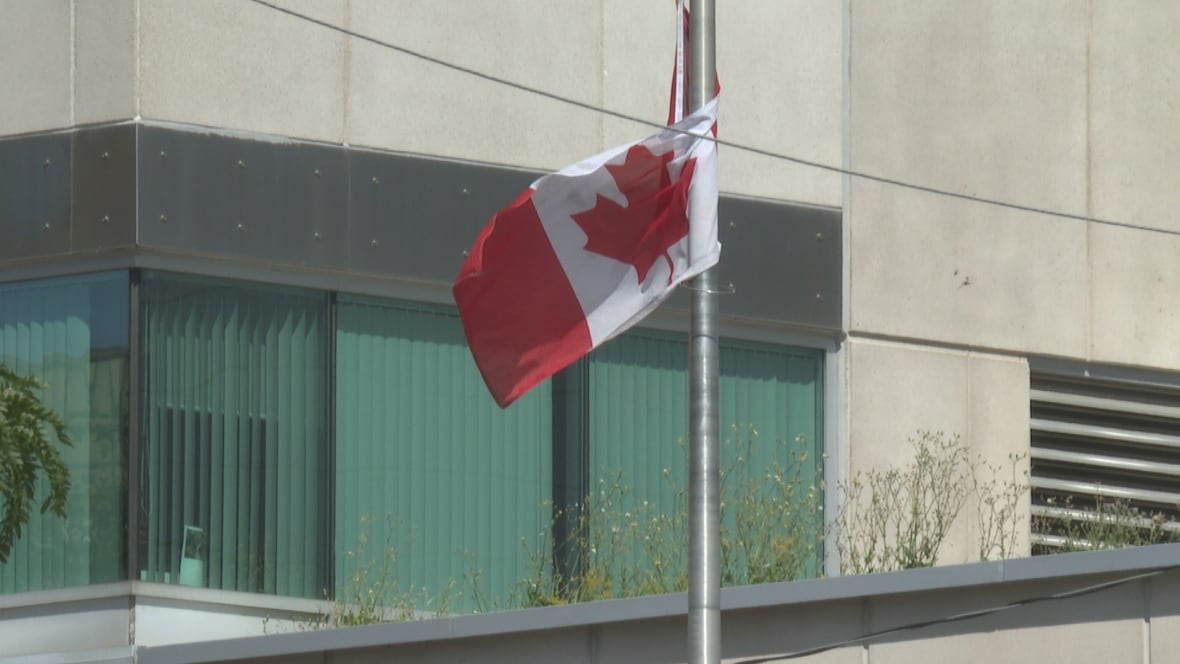 A Canadian flag over courthouse buildings.