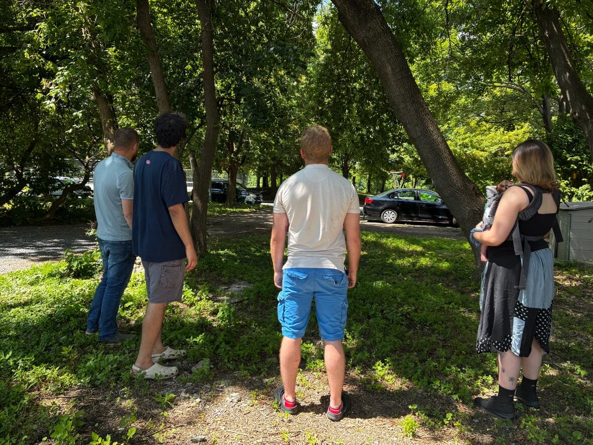 Four people look at a driveway.