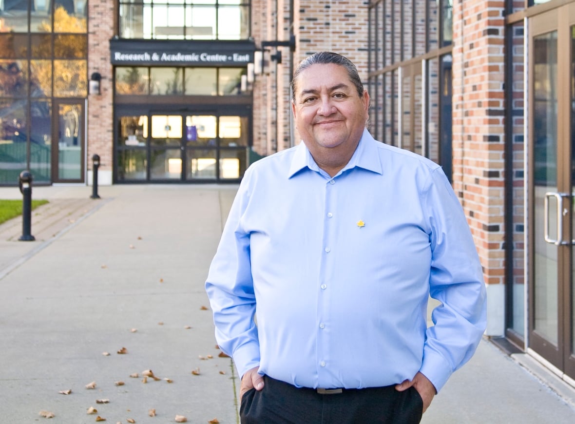 Photo of person outside with hands in his pockets, looking at the camera.