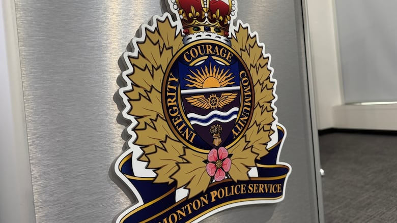 The Edmonton Police Service crest is seen on a grey background in a room.