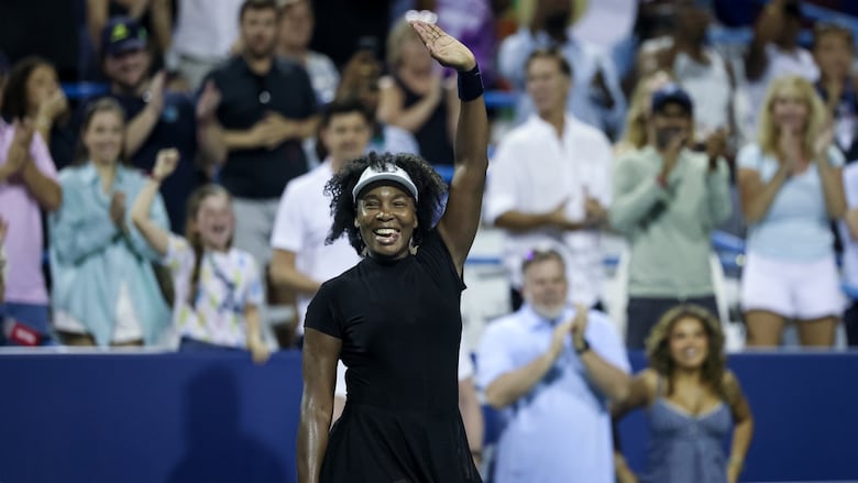 A women's tennis player celebrates and salutes the crowd after winning a match.