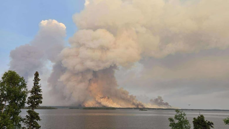 A huge fire burning in the distance across a lake 