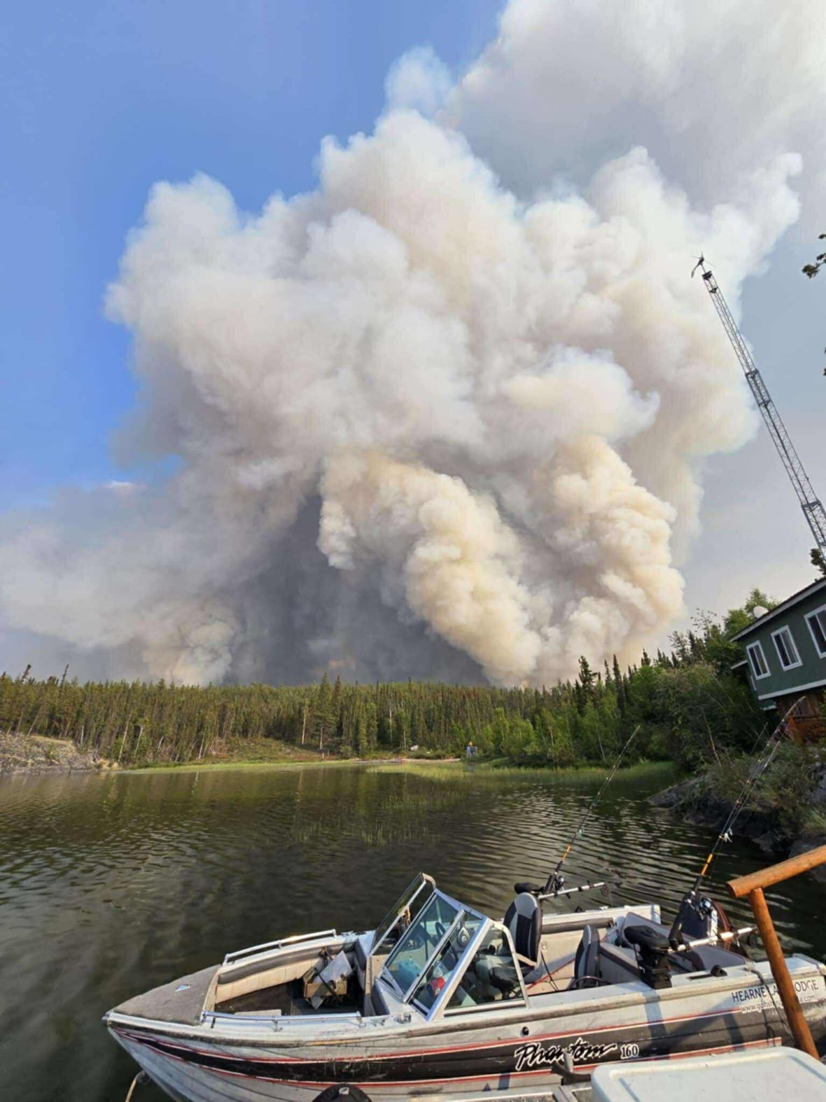 A boat and a cabin with a massive cloud of smoke in the background 