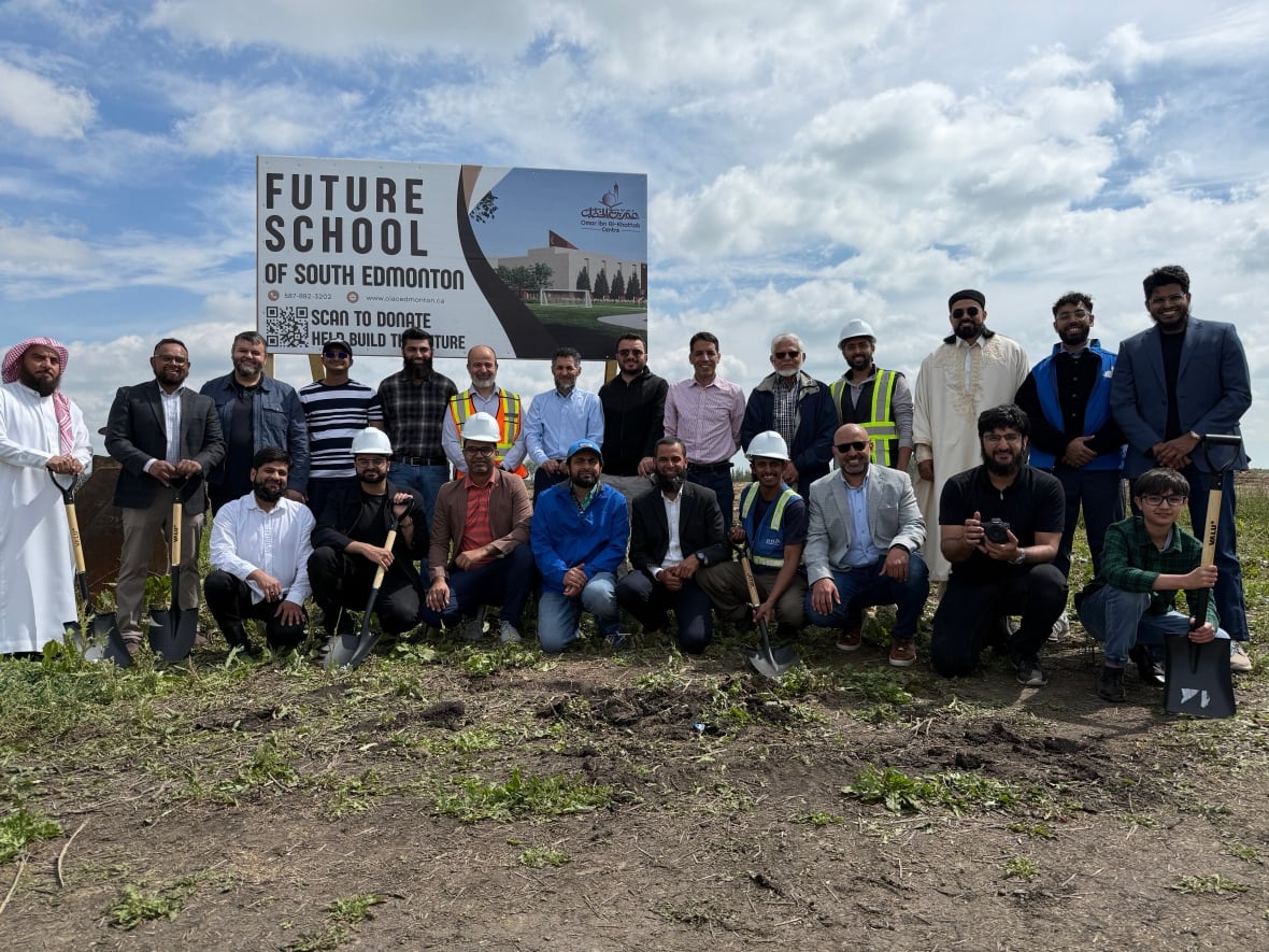 Community members, educators, builders and a student pose for photo at groundbreaking ceremony in front of photo of new school.