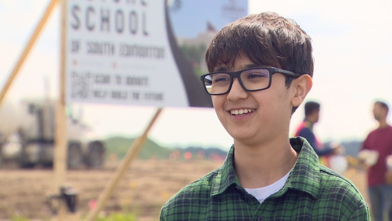 Smiling student does interview in front of construction site.