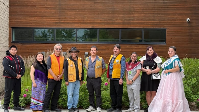 A group of people stand together wearing regalia.