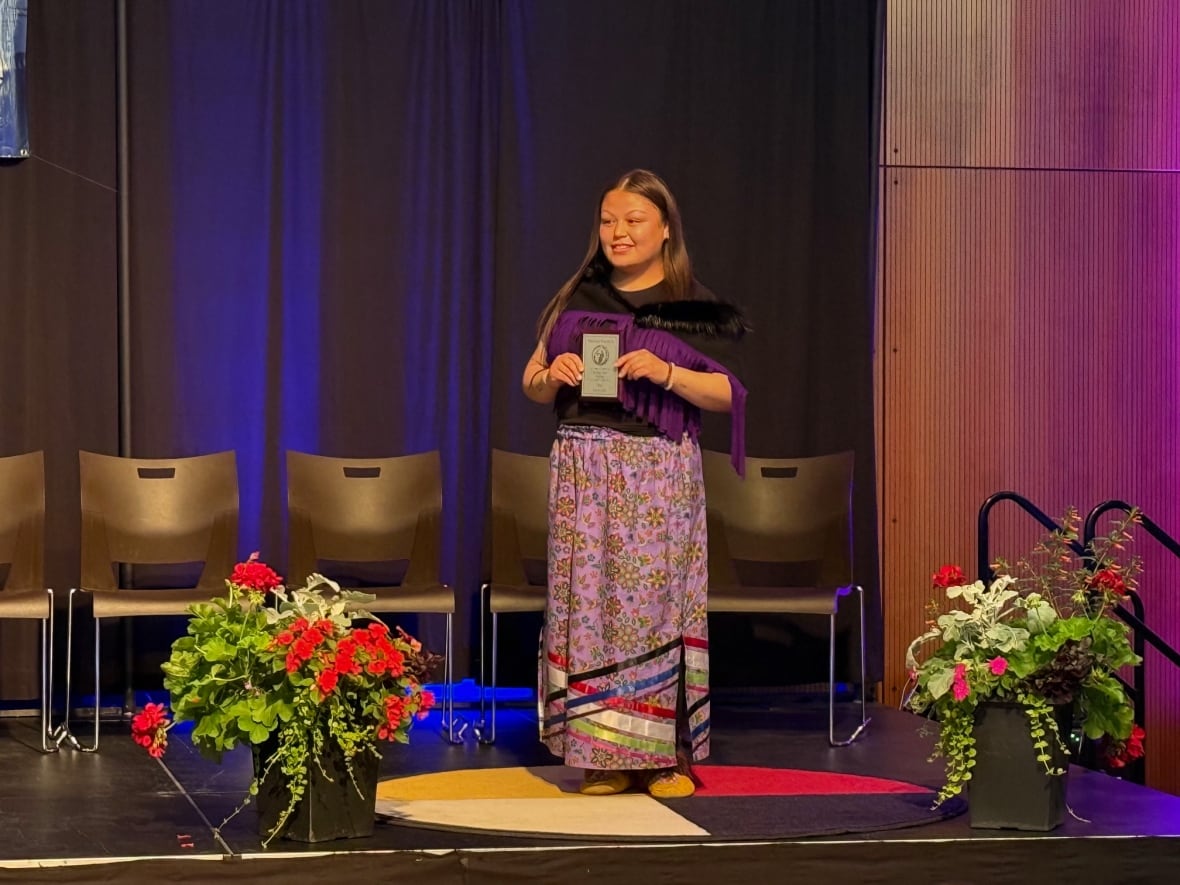 A young woman hopes a plaque on a stage.