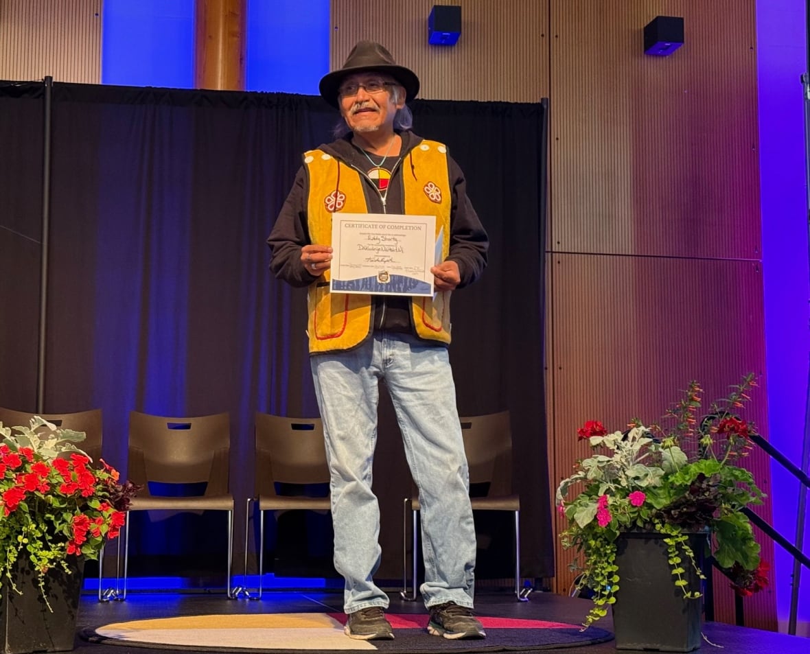 A man standing on a stage holding a certificate.