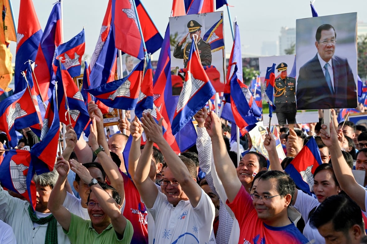 A number of people is shown in the outside show, rising the arms, by holding blue and red flags.