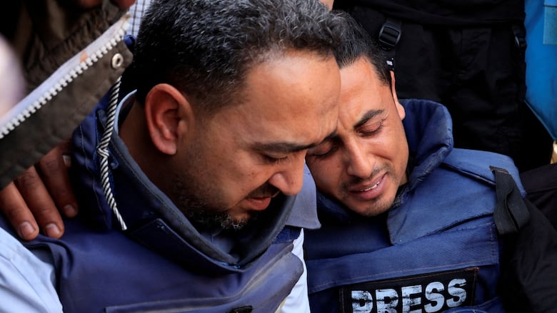Journalists react at a funeral for a colleague.