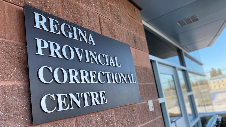 A plaque sits on a brick wall that reads "Regina Provincial Correctional Centre."