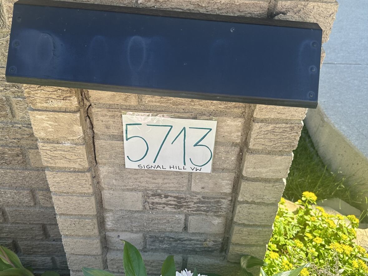 A piece of paper with an address written on it, attached to a brick post.