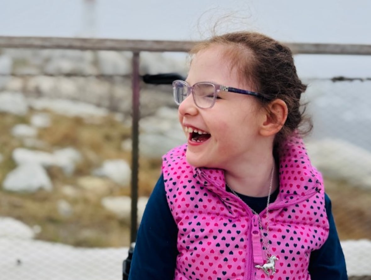 A young girl smiles on a foggy day