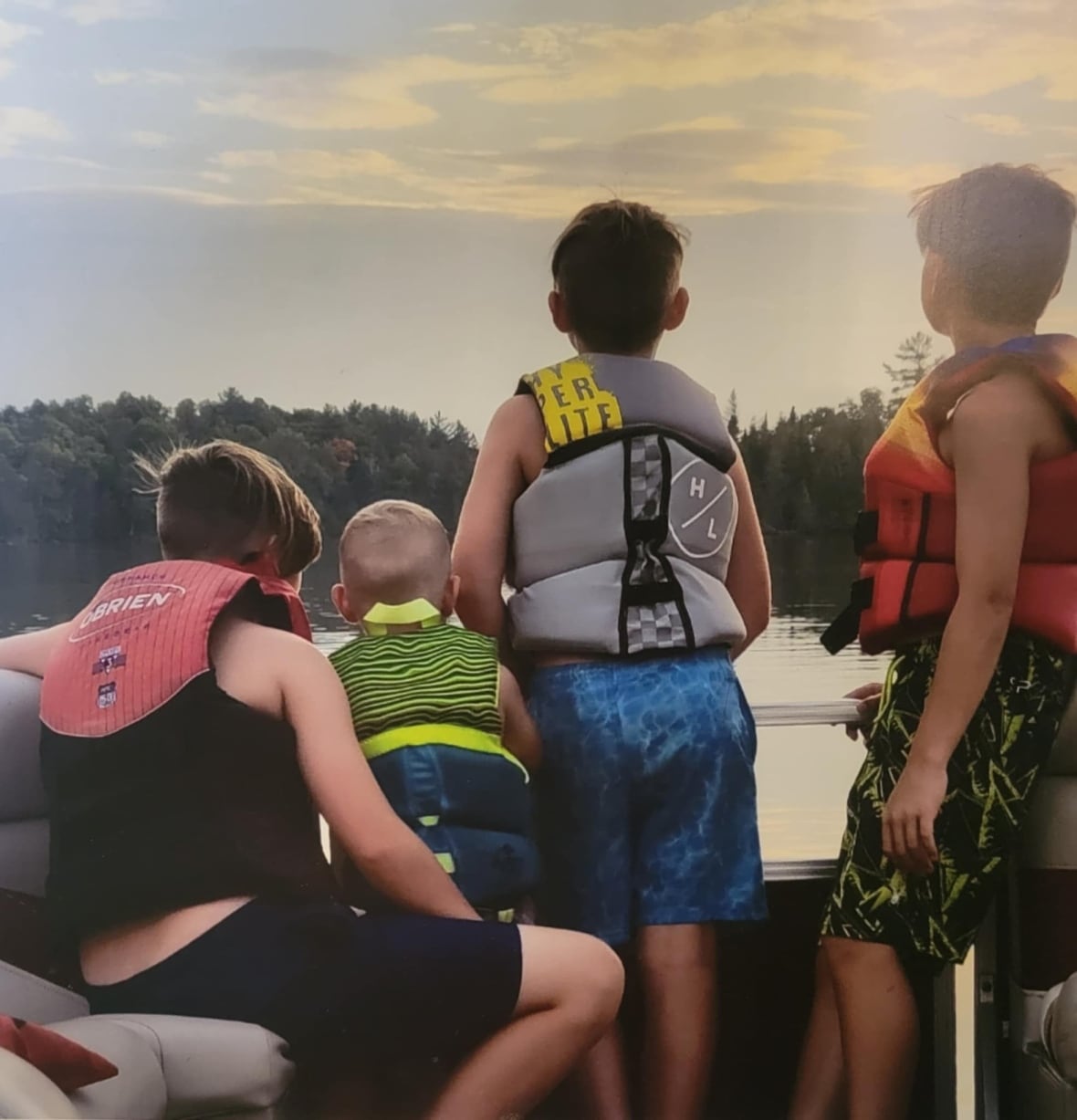 Four boys in life face water on a boat