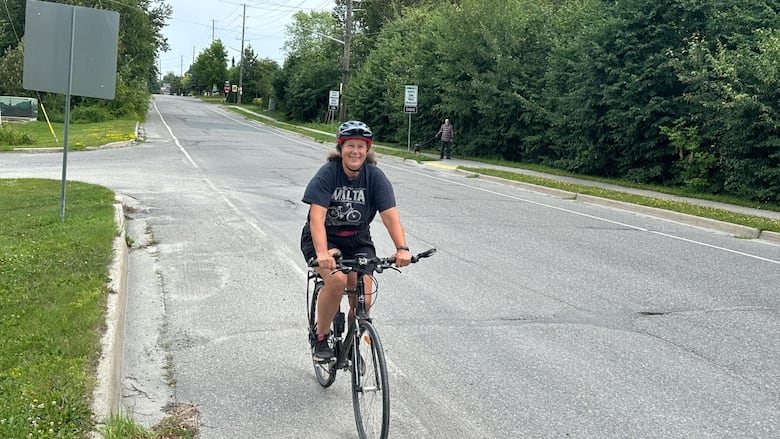 A woman riding a bicycle along a road.