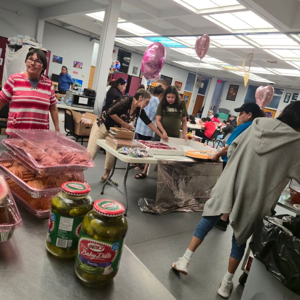 A group of people organize a gathering at a salon with balloons and cake.