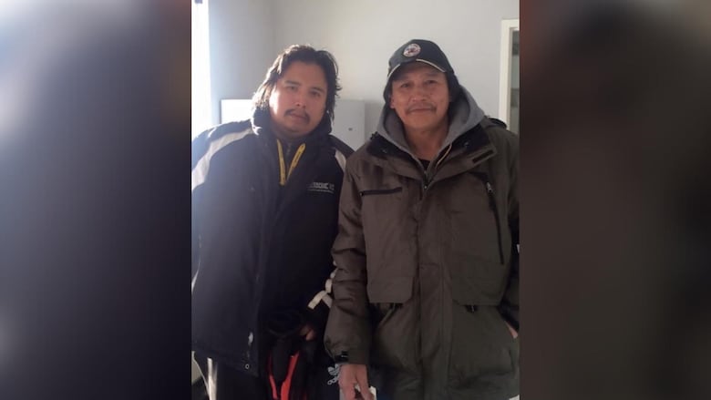 Two men wearing jackets are seen standing beside each other.