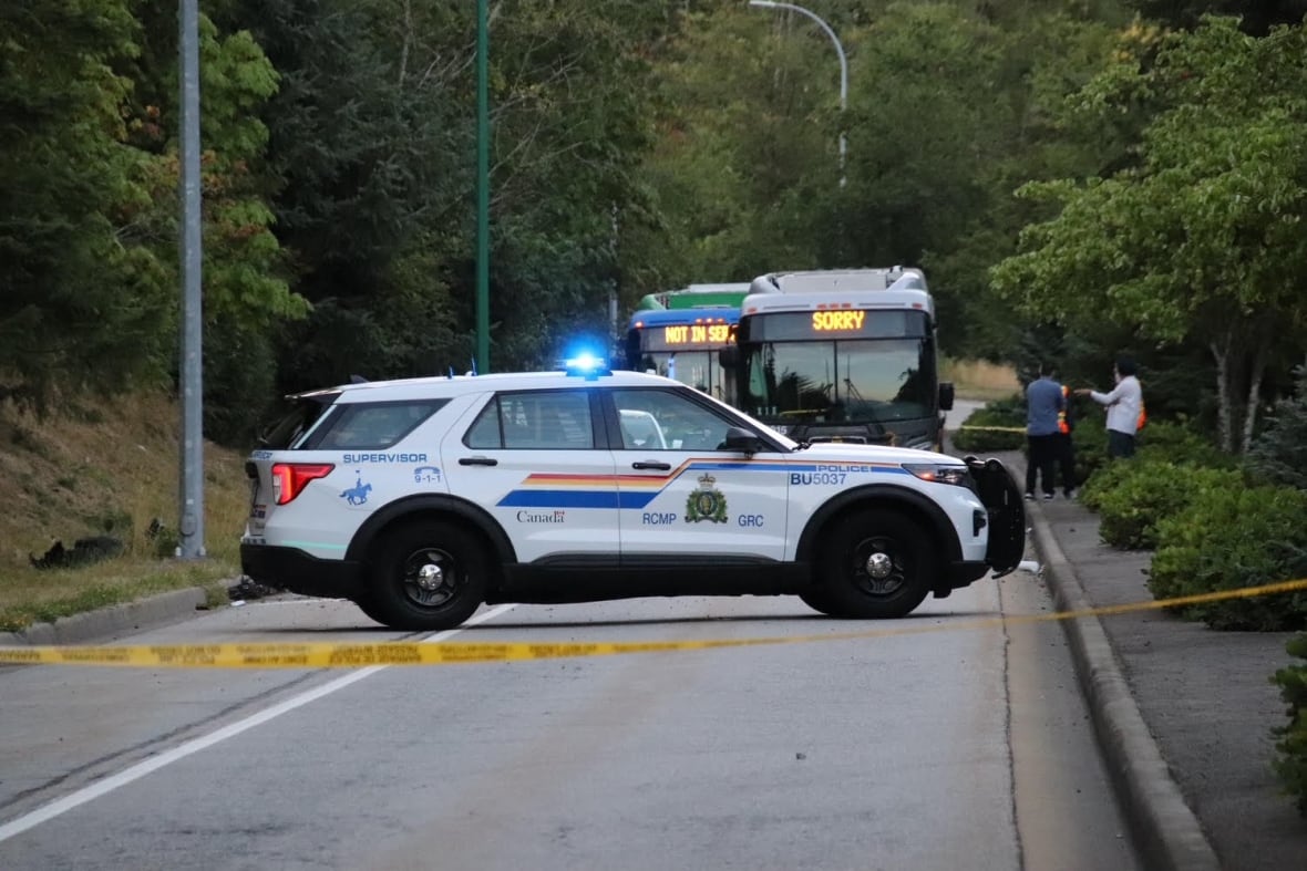 A police vehicle is seen behind police tape, and behind it two buses that appear to have been stopped.