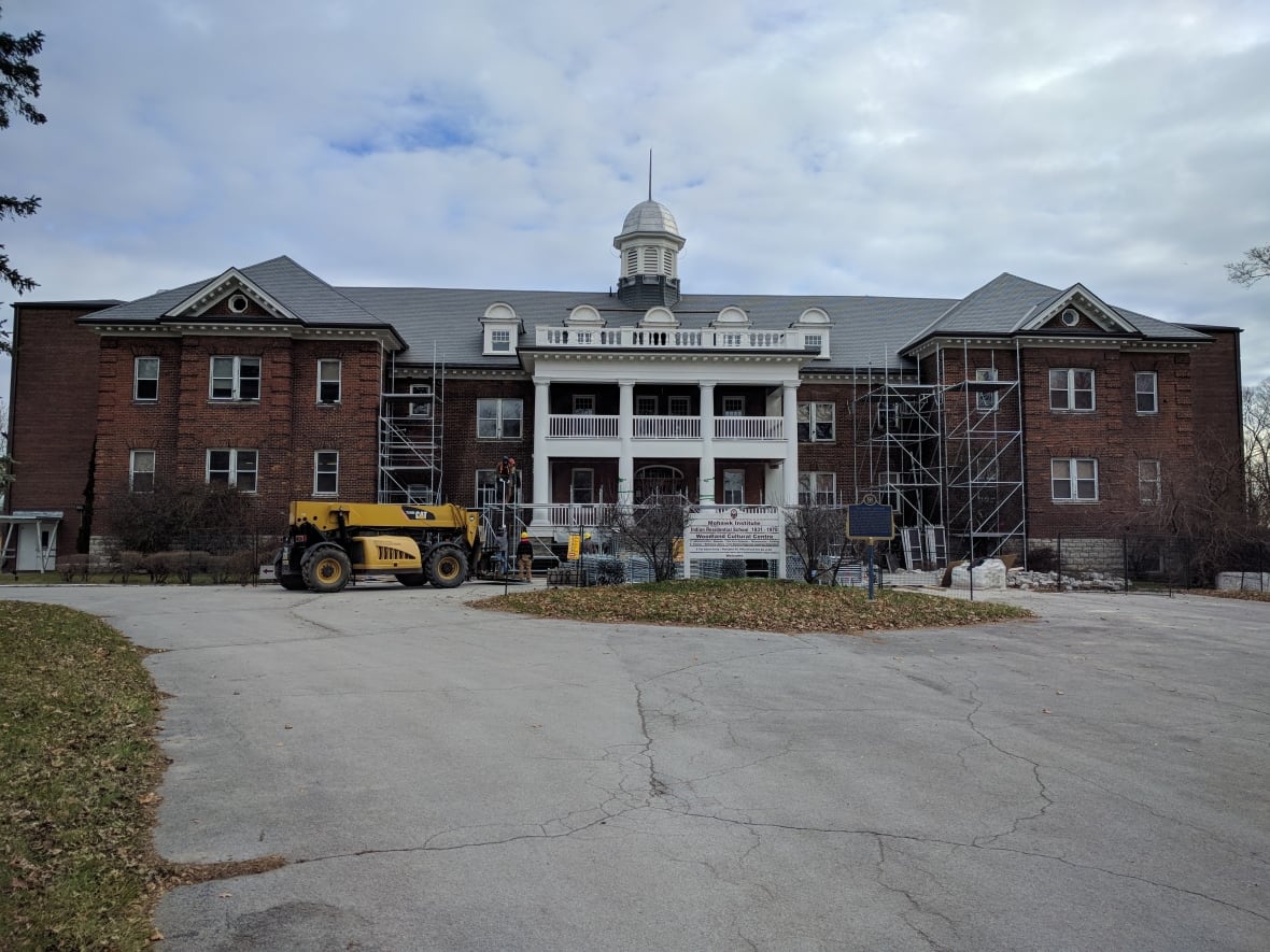 Shoddy building with scaffolding and trucks.